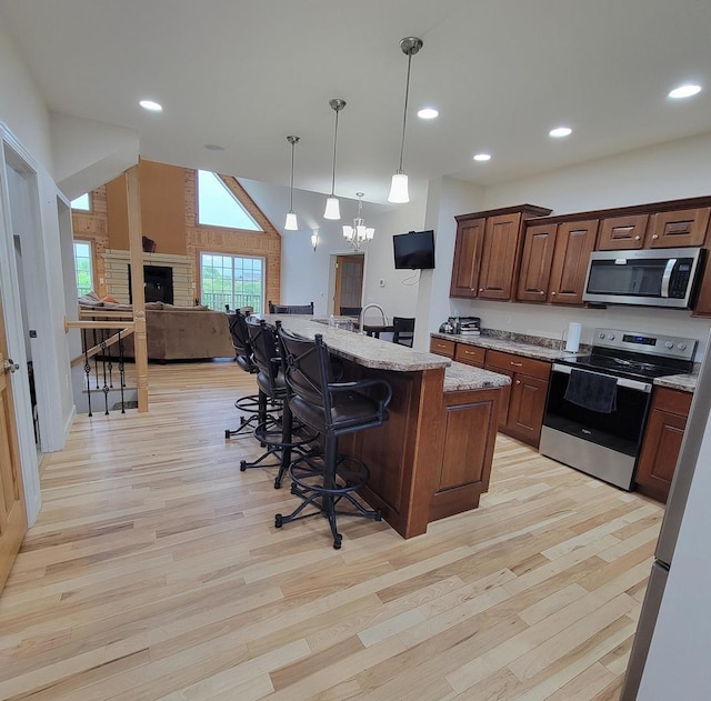 7648 N Indian Ridge Rd, East Dubuque, IL 61025 - kitchen with stainless steel appliances, a breakfast bar area, light wood-type flooring, open floor plan, and light stone countertops
