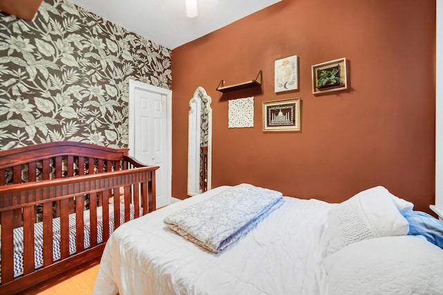 838 N Maplewood Ave Unit 1R, Chicago, IL 60622 - bedroom with wallpapered walls, wood finished floors, an accent wall, and a ceiling fan