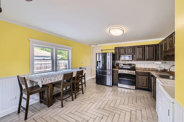 3007 Falcon Ct W, Rolling Meadows, IL 60008 - kitchen with stainless steel appliances, a sink, dark brown cabinets, decorative backsplash, and a wainscoted wall