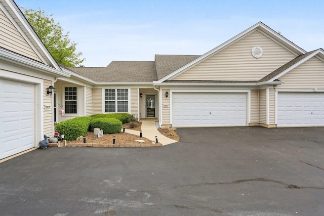 view of front facade with asphalt driveway, a garage, and a shingled roof