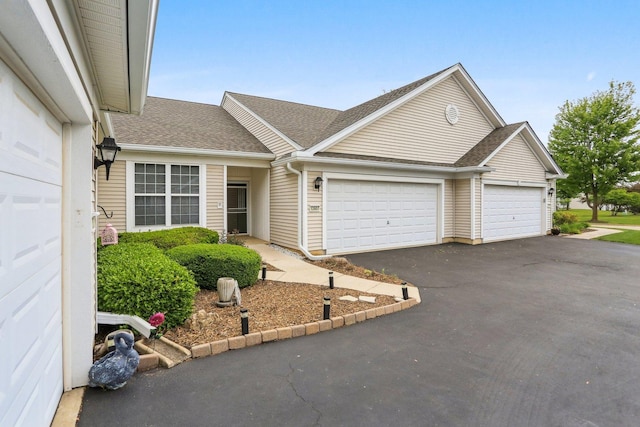 view of front facade with a garage, asphalt driveway, and a shingled roof