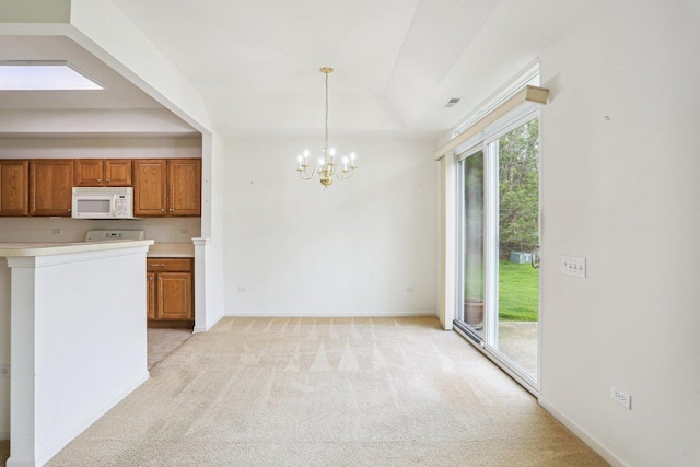 kitchen featuring white microwave, light colored carpet, a chandelier, brown cabinetry, and light countertops