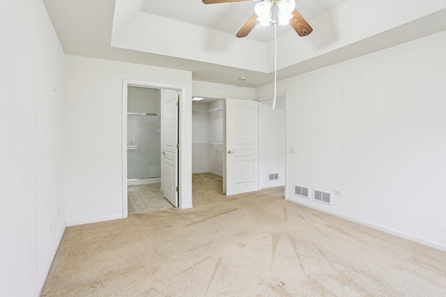 unfurnished bedroom with carpet floors, a spacious closet, a closet, baseboards, and ceiling fan