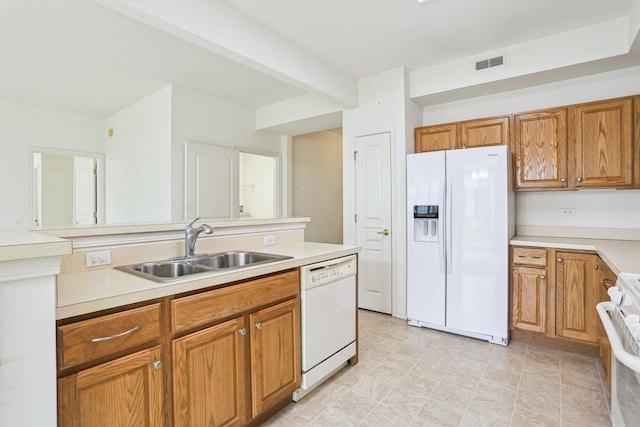 kitchen with white appliances, a sink, brown cabinets, and light countertops
