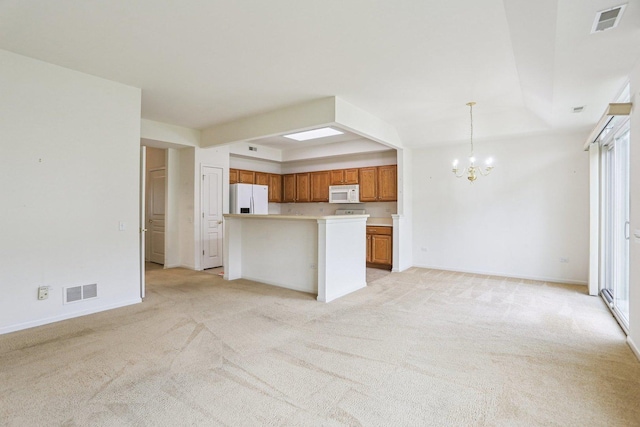 kitchen featuring white appliances, a chandelier, brown cabinets, light carpet, and open floor plan