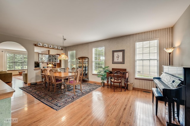 507 Parkland Ct, Oswego, IL 60543 - dining room featuring arched walkways, hardwood / wood-style flooring, wallpapered walls, and baseboards