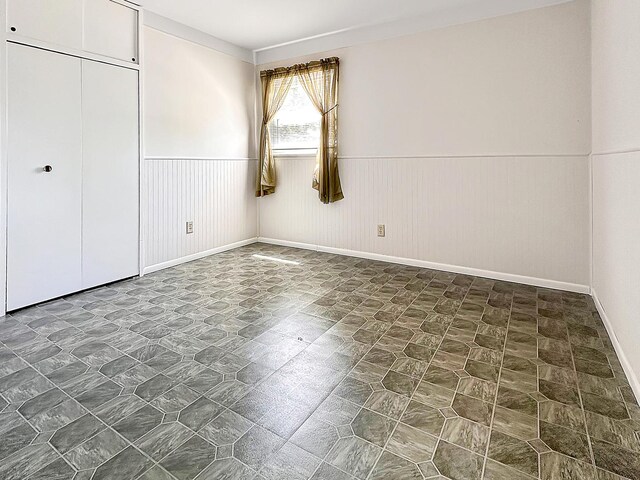 337 E Rose St, Glenwood, IL 60425 - unfurnished bedroom featuring a wainscoted wall, baseboards, and a closet