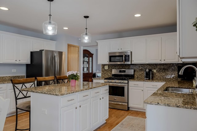 18132 Crystal Ln, Lansing, IL 60438 - kitchen featuring stainless steel appliances, a sink, light wood finished floors, a kitchen island, and white cabinetry