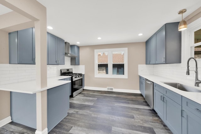 kitchen featuring stainless steel appliances, a sink, wall chimney exhaust hood, decorative backsplash, and baseboards