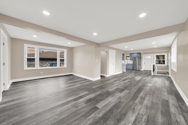 unfurnished living room featuring baseboards, dark wood-style flooring, and recessed lighting