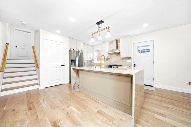 8619 Crawford Ave, Skokie, IL 60076 - kitchen featuring wall chimney range hood, stainless steel refrigerator with ice dispenser, white cabinetry, light stone countertops, and light wood-style floors