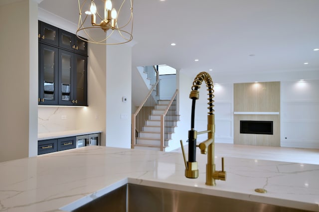 135 Lincoln St, Glenview, IL 60025 - kitchen with open floor plan, a fireplace, light stone counters, ornamental molding, and glass insert cabinets
