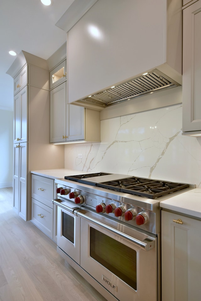 135 Lincoln St, Glenview, IL 60025 - kitchen with range with two ovens, custom range hood, light wood finished floors, backsplash, and glass insert cabinets