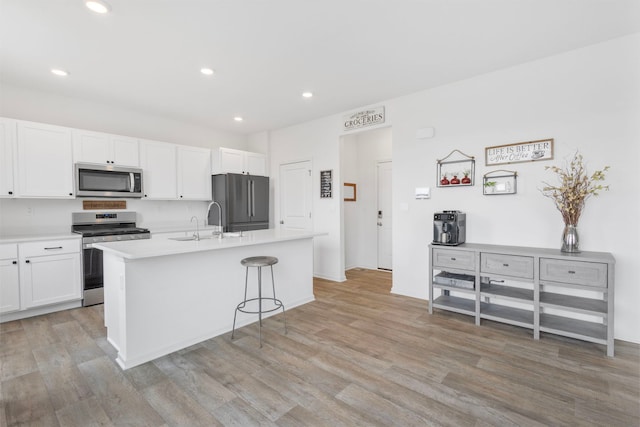2461 Tahoe Ln, Pingree Grove, IL 60140 - kitchen featuring stainless steel appliances, white cabinetry, light wood-style flooring, an island with sink, and recessed lighting