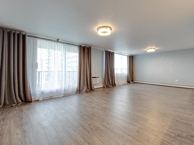 8801 W Golf Rd Unit 6J, Niles, IL 60714 - empty room featuring wood finished floors, a baseboard heating unit, and a wall mounted air conditioner