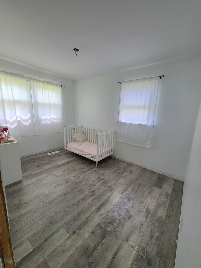bedroom featuring wood finished floors and a crib