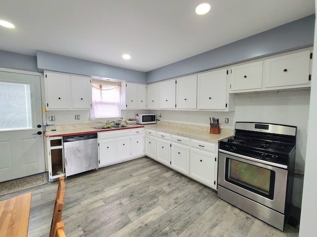 kitchen with stainless steel appliances, light countertops, white cabinetry, and recessed lighting