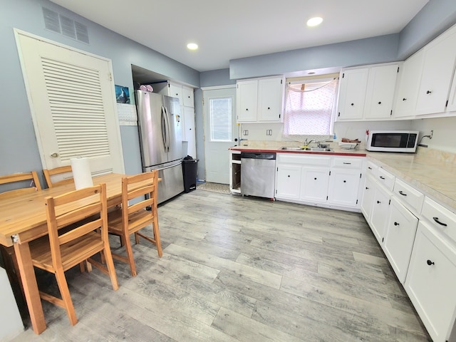 kitchen with appliances with stainless steel finishes, white cabinets, light wood-style floors, light countertops, and recessed lighting
