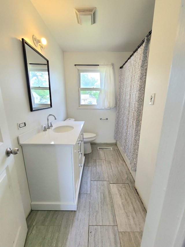 bathroom with vanity, toilet, wood finished floors, and curtained shower