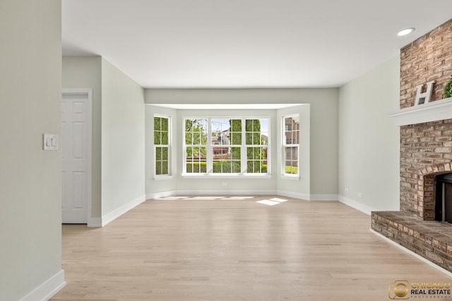 23653 W Ewing Dr, Plainfield, IL 60586 - unfurnished living room with baseboards, light wood-type flooring, and a fireplace