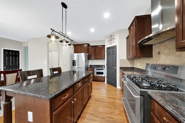 26809 Ashgate Xing, Plainfield, IL 60585 - kitchen with stainless steel appliances, wall chimney range hood, a kitchen breakfast bar, light wood-type flooring, and a kitchen island
