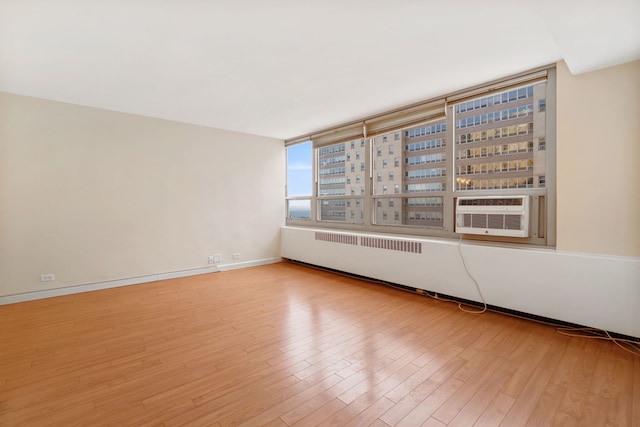 spare room with wood finished floors, cooling unit, and baseboards