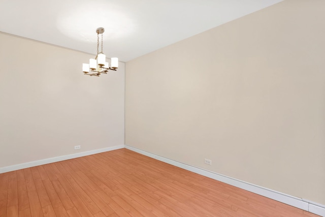 unfurnished room featuring a chandelier, baseboards, and light wood-style flooring