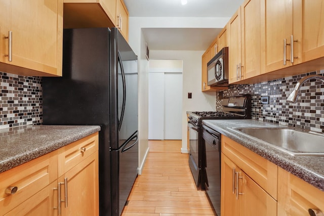 kitchen featuring black appliances, a sink, light brown cabinetry, and dark countertops