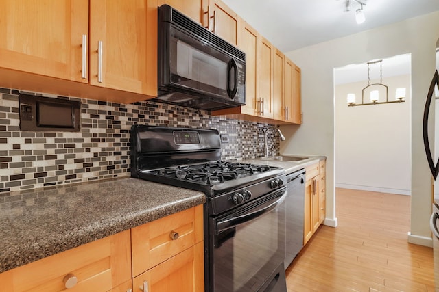kitchen featuring black appliances, a sink, light brown cabinetry, and tasteful backsplash