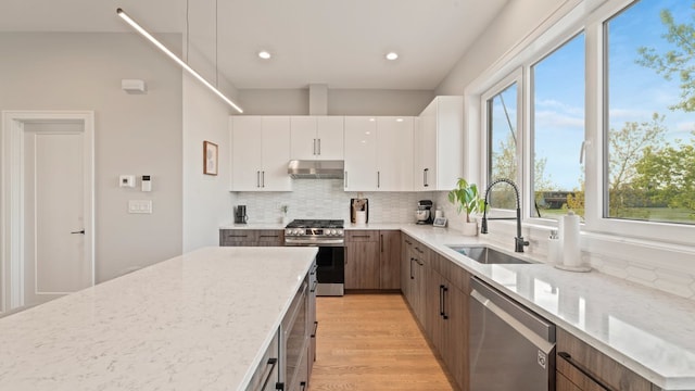 3124 S Benson St Unit 6, Chicago, IL 60608 - kitchen featuring stainless steel appliances, under cabinet range hood, a sink, decorative backsplash, and light stone counters