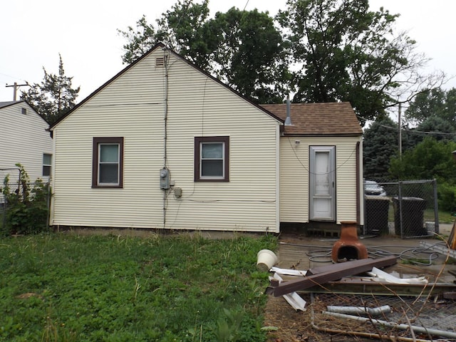 rear view of house with roof with shingles