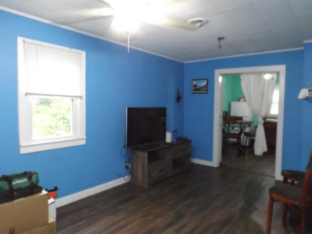 living area featuring wood finished floors, baseboards, and ornamental molding