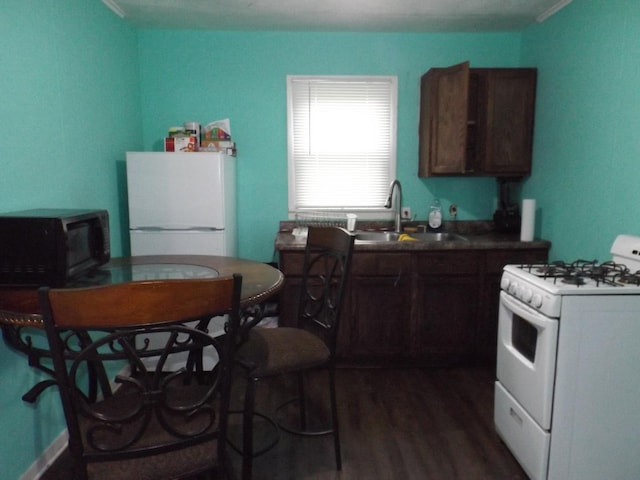 kitchen with white appliances, a sink, dark wood-style floors, and dark countertops