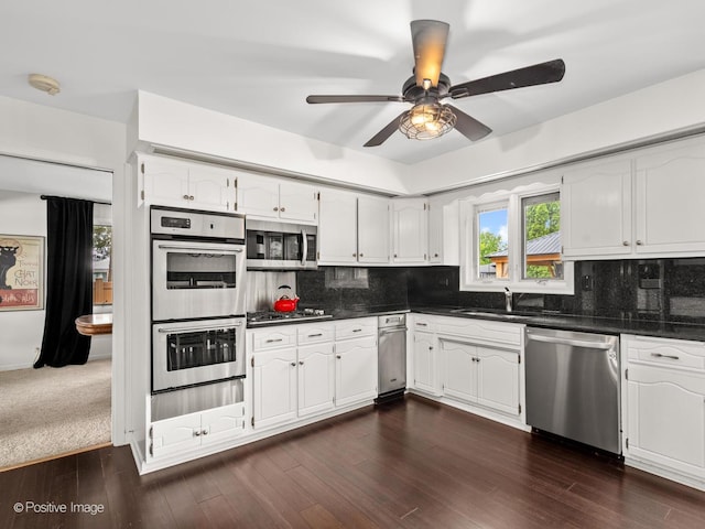 7235 Kiowa Ln, Palos Heights, IL 60463 - kitchen featuring appliances with stainless steel finishes, dark countertops, a sink, a ceiling fan, and white cabinetry
