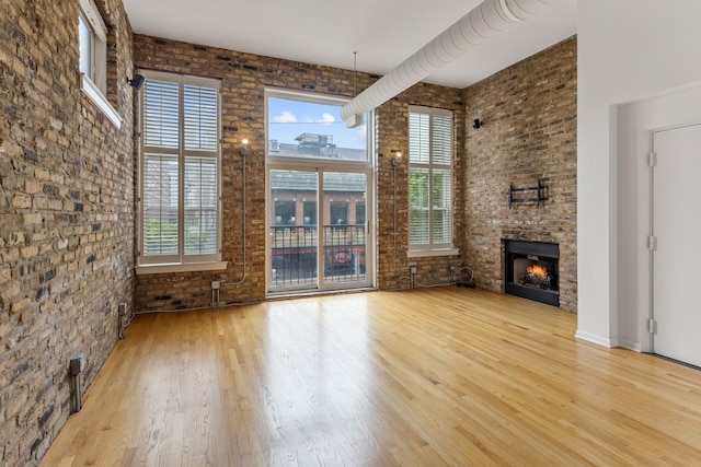 1012 W Diversey Pkwy Unit 2, Chicago, IL 60614 - unfurnished living room with wood finished floors, a fireplace, brick wall, and a towering ceiling