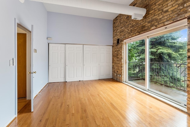 1012 W Diversey Pkwy Unit 2, Chicago, IL 60614 - unfurnished bedroom featuring light wood-style floors, a towering ceiling, brick wall, and a closet