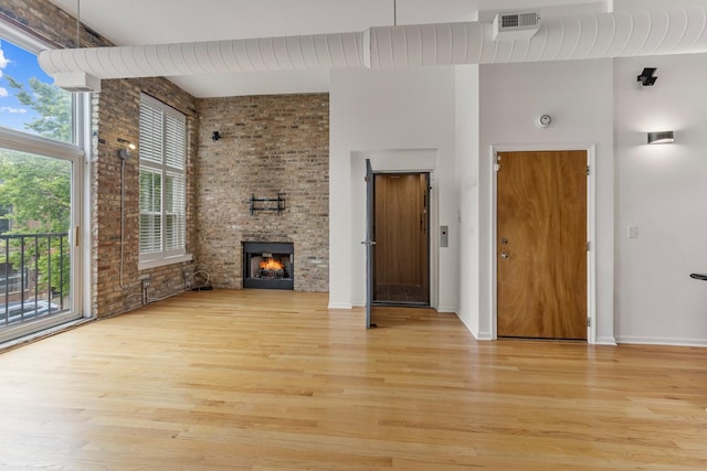 1012 W Diversey Pkwy Unit 2, Chicago, IL 60614 - unfurnished living room featuring light wood-style flooring, a towering ceiling, a large fireplace, and baseboards