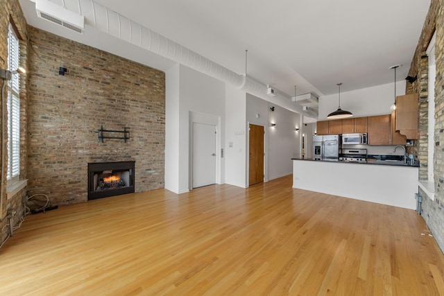 1012 W Diversey Pkwy Unit 2, Chicago, IL 60614 - unfurnished living room with a high ceiling, light wood-style flooring, a brick fireplace, and a sink