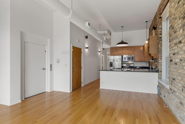 1012 W Diversey Pkwy Unit 2, Chicago, IL 60614 - kitchen featuring appliances with stainless steel finishes, dark countertops, a towering ceiling, light wood-style floors, and brown cabinetry