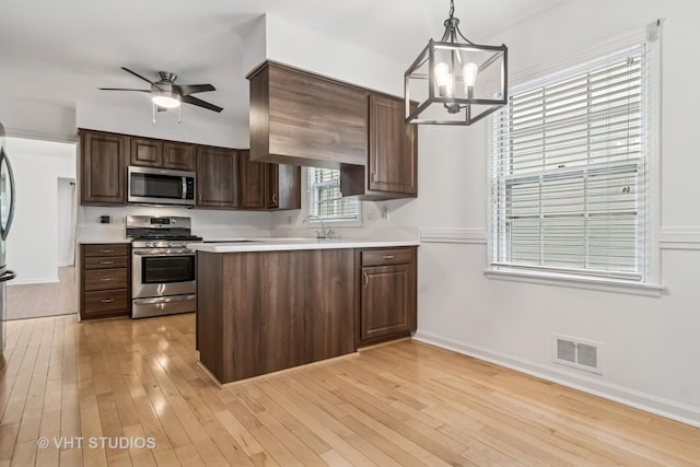 827 Forest Ave, River Forest, IL 60305 - kitchen featuring appliances with stainless steel finishes, light countertops, a peninsula, light wood finished floors, and a chandelier
