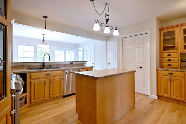 kitchen featuring stainless steel dishwasher, a sink, a kitchen island, light wood finished floors, and pendant lighting