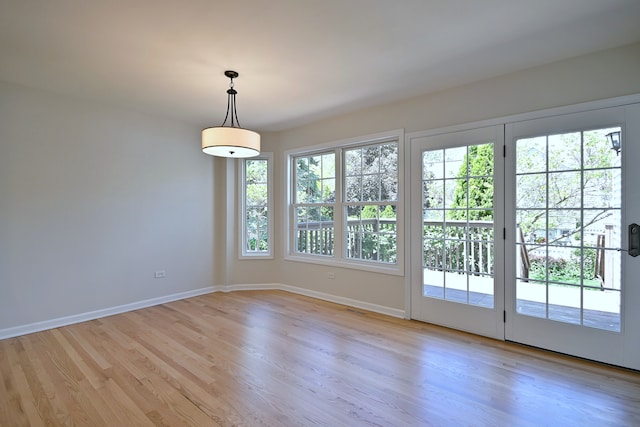 unfurnished dining area with light wood-type flooring and baseboards