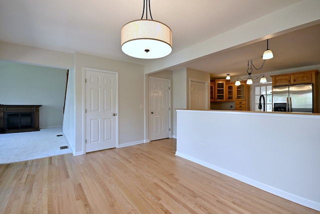 unfurnished living room with light wood-style floors, a glass covered fireplace, and baseboards