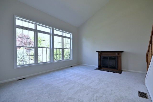 unfurnished living room featuring carpet flooring, baseboards, a fireplace with flush hearth, and high vaulted ceiling
