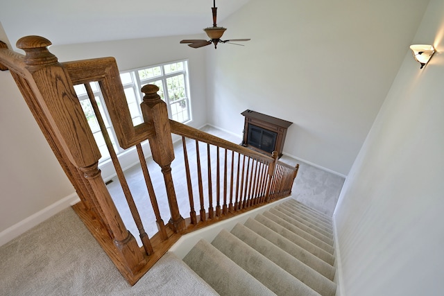 staircase with carpet floors, baseboards, ceiling fan, and vaulted ceiling