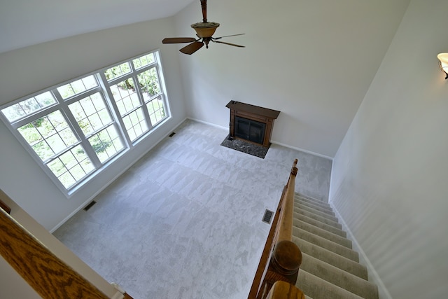 unfurnished living room with carpet floors, a fireplace with flush hearth, baseboards, a ceiling fan, and vaulted ceiling