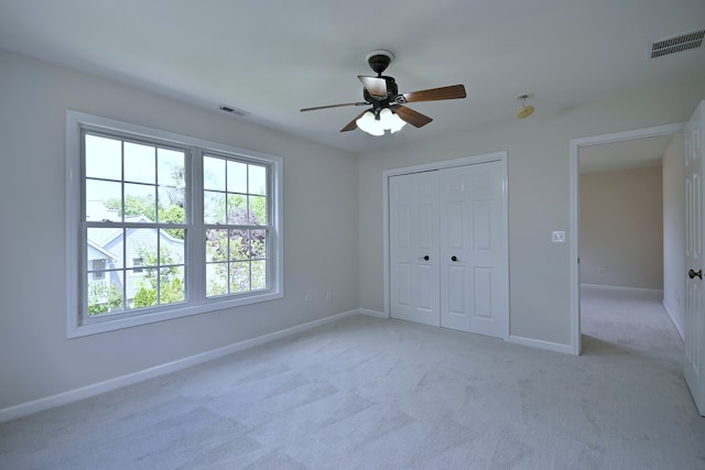 unfurnished bedroom featuring light carpet, baseboards, a closet, and ceiling fan