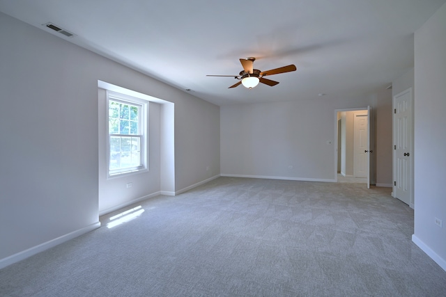 spare room featuring a ceiling fan, light colored carpet, and baseboards