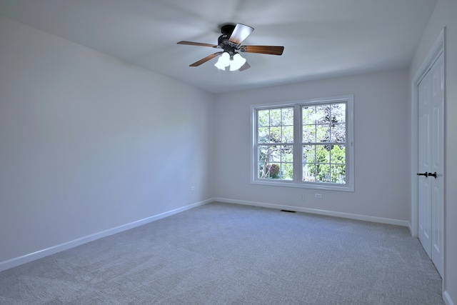 carpeted empty room with a ceiling fan and baseboards