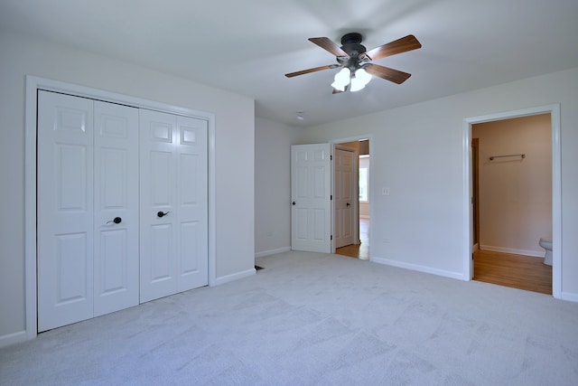 unfurnished bedroom featuring carpet, a closet, connected bathroom, baseboards, and a ceiling fan